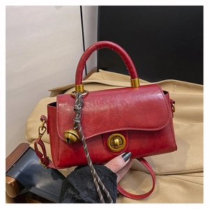 Detailed macro of dark red vintage leather handbag with gold twist lock and bell charm