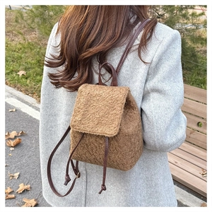 Rear view of model wearing a brown fuzzy wool backpack with slim leather straps