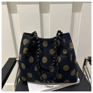 Close-up of retro wool tote bag featuring navy base with green polka dots and chain handles
