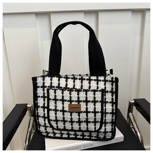 Detail of tweed checkered tote bag with branded leather patch on front pocket