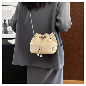 Détail du sac seau beige avec papillons argentés et finitions en perles élégantes
