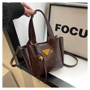 Detail view of dark brown vintage tote bag with gold triangle logo and tassel accent