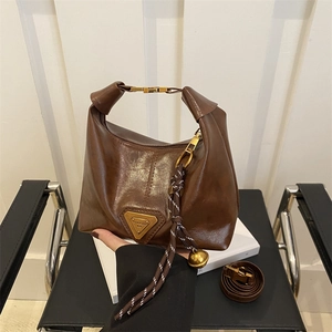 Vintage dark brown half-moon bag with gold metal plaque and woven bell pendant detail
