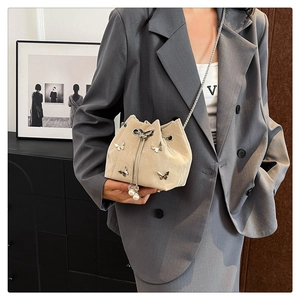 Détail du sac seau plissé beige avec fermoir papillon et glands en grosses perles