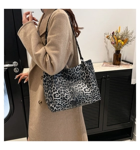 Detailed view of leopard print tote bag with black strap on elegant beige coat