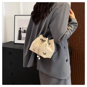 Détail du sac seau crème à cordon avec papillons argentés et grandes perles de charme