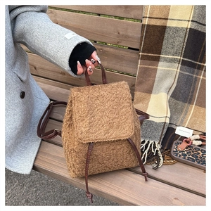 Close-up of brown faux fur backpack with leather straps against a winter coat background