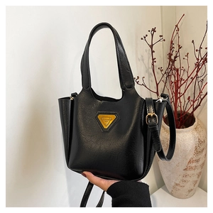 Close-up of black textured faux leather handbag with golden triangle metal logo detail