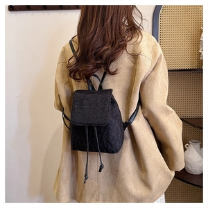 Detail of black faux shearling mini backpack with drawstring closure and slim straps