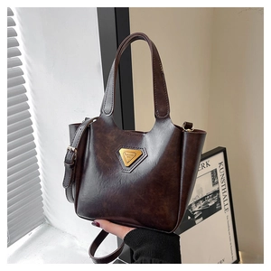 Detail of dark brown tote bag featuring glossy leather texture and gold metal logo