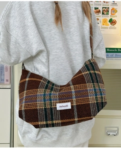 Detail showing vintage plaid wool dumpling bag with textile label worn on the shoulder