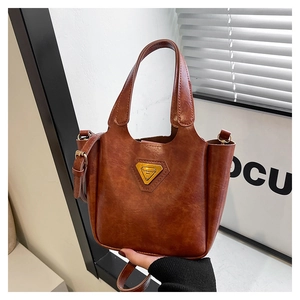 Close-up of brown oiled leather tote bag with gold triangle hardware and handle detail