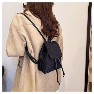 Close-up of black wool texture mini backpack with drawstring and flap closure