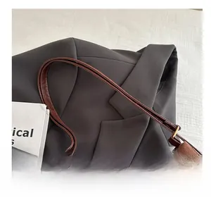 Detail shot of brown suede tote bag featuring slim leather straps and textured material
