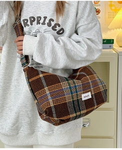 Brown plaid wool dumpling bag shown as a crossbody with a wide shoulder strap
