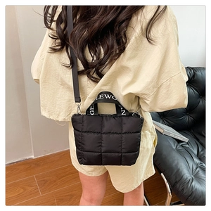 Rear view of a black quilted puffer bag with branded wide handles and crossbody strap