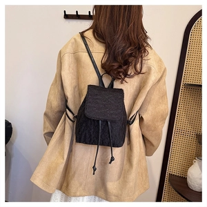 Detail of black tweed backpack with textured finish shown on model in cozy setting