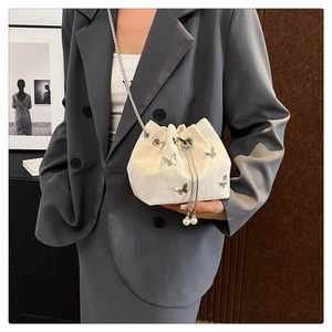 Détail du sac seau blanc avec breloques papillon en argent et perles sur le cordon