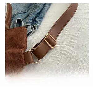 Detailed close-up of brown suede bag strap with adjustable gold metallic hardware buckle