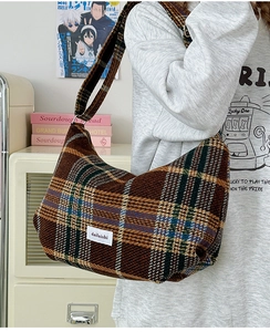 Detail of vintage brown plaid wool hobo bag worn by a model in a cozy indoor setting