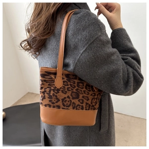 Close-up of leopard print bucket bag with brown PU leather trim worn over an overcoat
