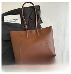 Detail of brown matte leather tote bag styled with a professional grey blazer for office