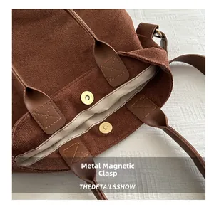 Close-up of the metal magnetic buckle and suede texture on a brown tote bag