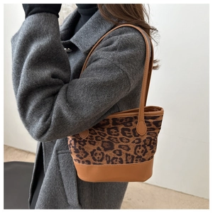 Detail of leopard print bucket bag featuring brown faux leather handles and texture