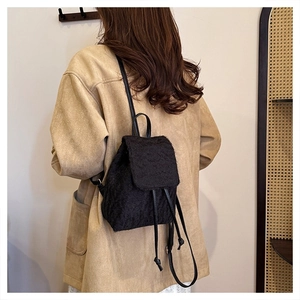 Detail view of mini black plush backpack with faux fur texture and drawstring on female model
