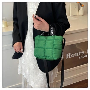 Detail of green quilted down crossbody bag with branded lettering straps and long shoulder strap