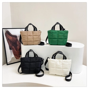 Close-up of quilted puffy tote bags in khaki green black and white colors with logo straps