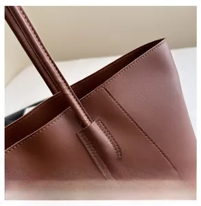 Close-up of the meticulous stitching and handle attachment on this brown tote bag