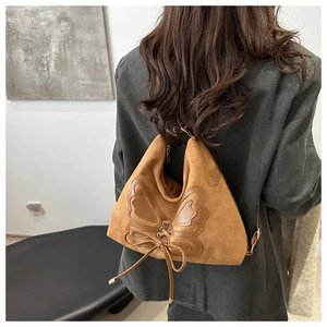 Detail of vintage brown suede shoulder bag with leather bow and tassel on a model