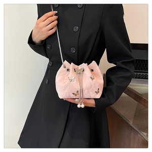 Détail du sac seau rose avec papillons dorés, cordon de serrage et perles blanches