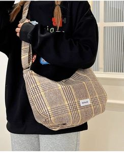 Detail shot of the textured plaid fabric and woven brand label on a retro crossbody bag
