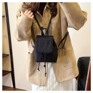 Mini black faux fur backpack shown on model in a warm interior lifestyle setting