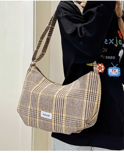 Detail of vintage plaid woolen fabric texture and woven brand label on the crossbody bag