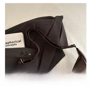 Detail of a dark brown hobo bag with a leopard bow bear charm on a grey suit jacket