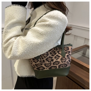 Detail of leopard print bucket bag with green leather trim on a model in a studio