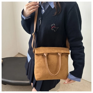 Detailed close-up of brown suede tote bag with slim handles and adjustable shoulder strap