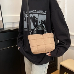Beige quilted puffer tote bag with black lettered straps and adjustable shoulder strap