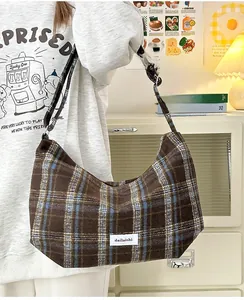 Detail shot of vintage plaid hobo bag in brown and blue with adjustable strap and brand tag