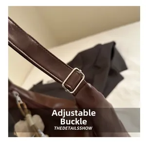 Detail of dark brown leather tote strap with adjustable silver buckle and plush charm