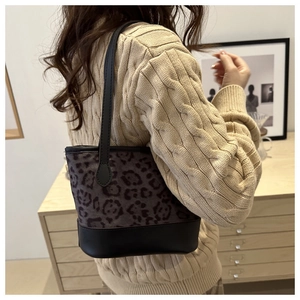 Close-up of leopard jacquard bucket bag with black leather base worn by a model