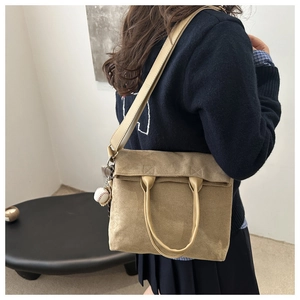 Detail of khaki shoulder bag with leather handle and decorative baseball keychain