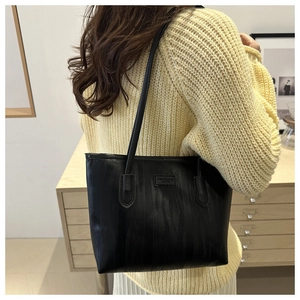 Detail view of black tote bag featuring unique vertical wave texture and fashion label