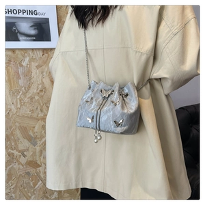 Détail du sac seau plissé argenté avec papillons métalliques et chaîne en perles