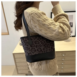 Close-up of leopard print tote bag with black leather base worn with beige sweater
