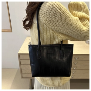 Side view of a black large capacity tote bag with embossed texture worn by a model