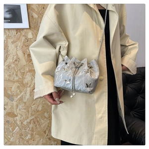 Détail du sac seau plissé argenté avec breloques papillon en métal et accents de perles